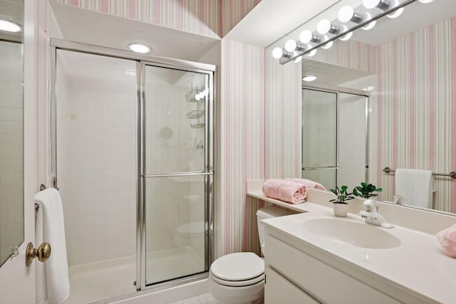 full bathroom with vanity, toilet, a shower stall, and wallpapered walls