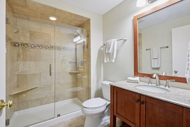 full bath featuring a stall shower, toilet, and vanity