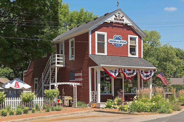 victorian home featuring stairs, fence, and a shingled roof