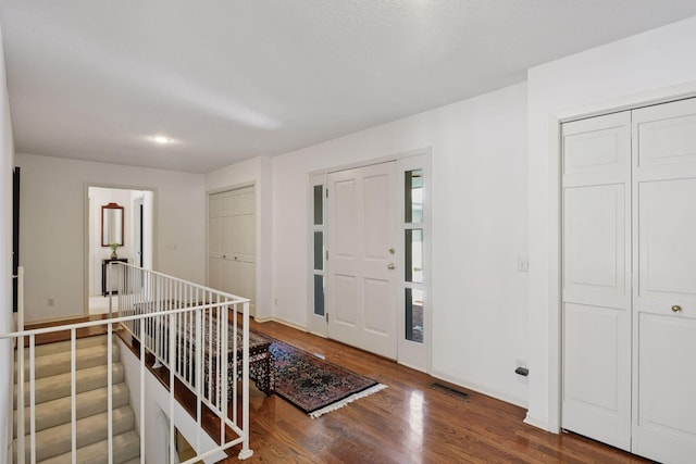 foyer entrance featuring visible vents, baseboards, and wood finished floors