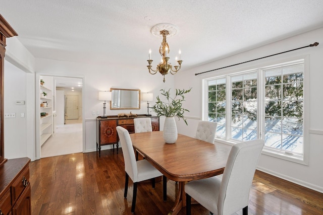 dining area featuring dark wood-type flooring, a notable chandelier, a healthy amount of sunlight, and a textured ceiling