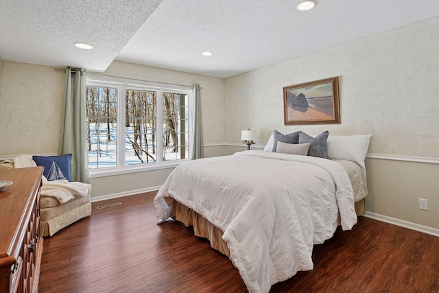 bedroom with baseboards, wood finished floors, and a textured ceiling