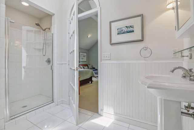 ensuite bathroom featuring wainscoting, lofted ceiling, ensuite bath, tile patterned flooring, and a shower stall