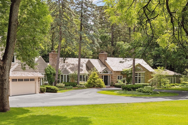 view of front of property with a garage, a chimney, aphalt driveway, and a front yard