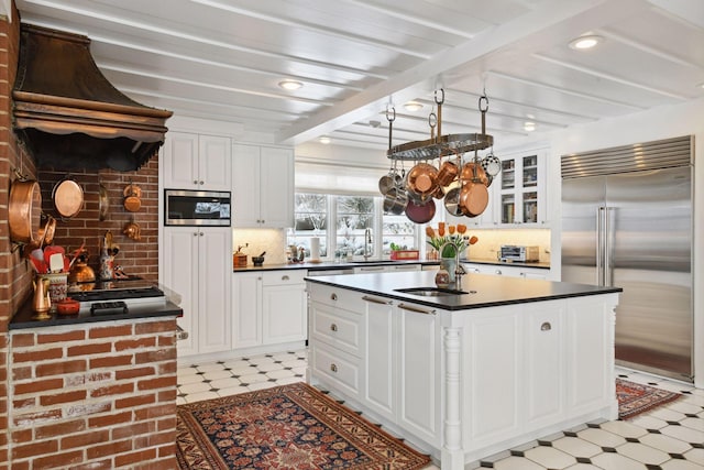 kitchen featuring dark countertops, custom exhaust hood, light floors, and built in appliances