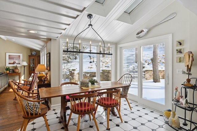 dining area featuring vaulted ceiling with beams, a healthy amount of sunlight, a chandelier, and light floors