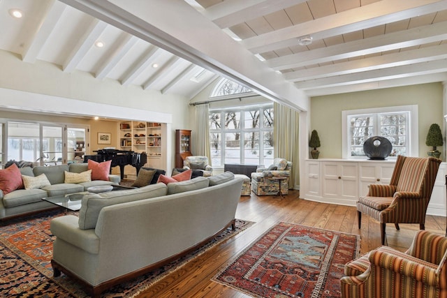 living area featuring vaulted ceiling with beams, light wood-type flooring, plenty of natural light, and built in features