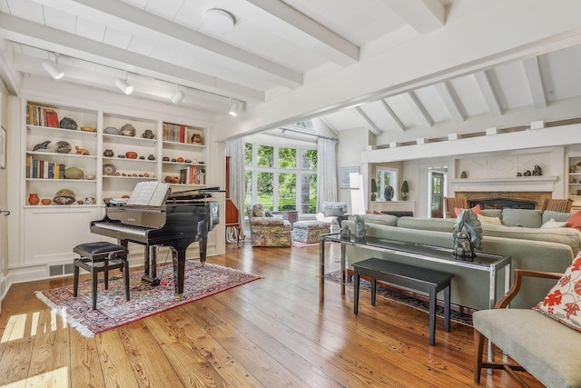 sitting room featuring lofted ceiling with beams, hardwood / wood-style floors, rail lighting, built in shelves, and a fireplace