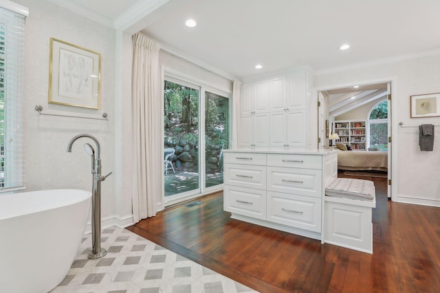 bathroom with ornamental molding, a freestanding bath, and hardwood / wood-style floors