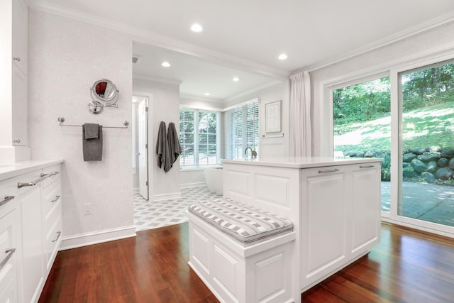 interior space featuring recessed lighting, a freestanding bath, ornamental molding, wood finished floors, and baseboards