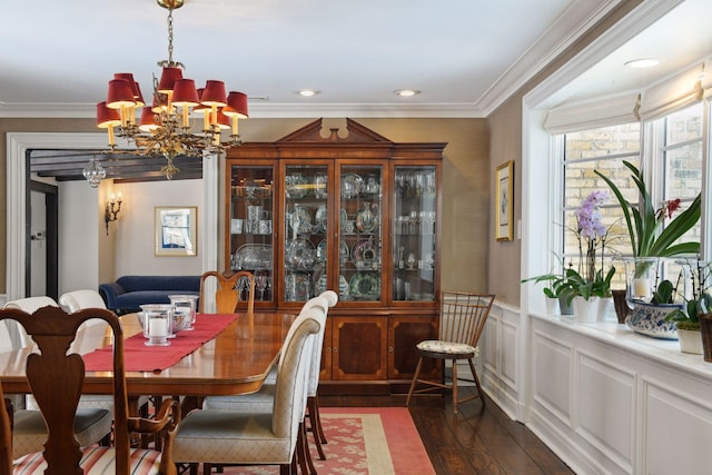 dining area featuring wainscoting, a chandelier, dark wood-type flooring, and ornamental molding