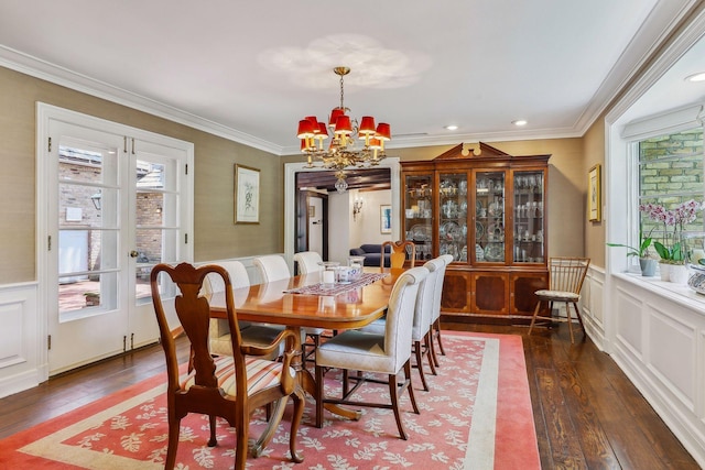 dining room featuring hardwood / wood-style flooring, a chandelier, crown molding, and a wainscoted wall