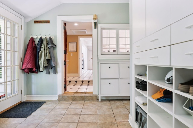 interior space with lofted ceiling, light tile patterned floors, baseboards, and a wealth of natural light