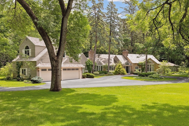 view of front of house featuring aphalt driveway, a front lawn, and a chimney