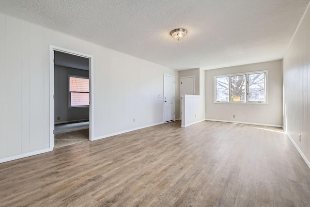 unfurnished bedroom with a textured ceiling, baseboards, and wood finished floors