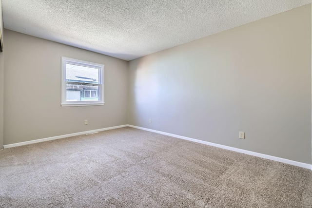 carpeted spare room featuring baseboards and a textured ceiling