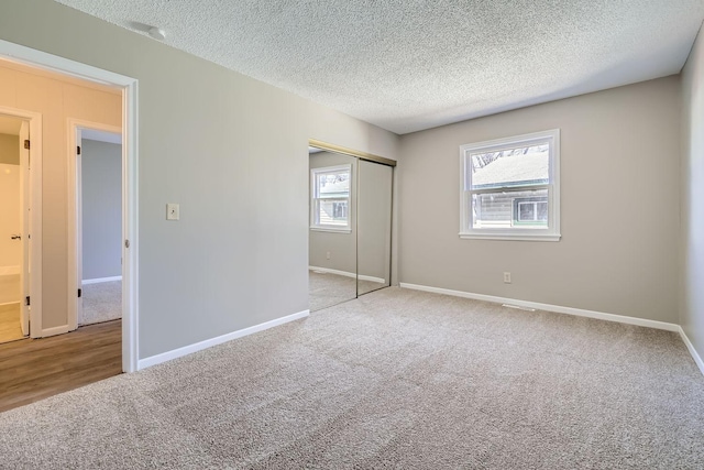 unfurnished bedroom featuring a textured ceiling, a closet, carpet, and baseboards