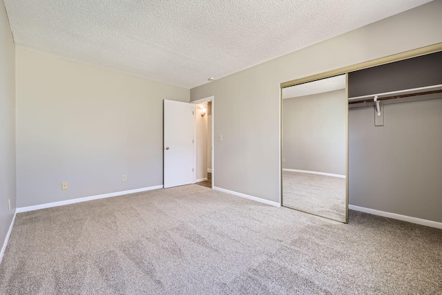 unfurnished bedroom featuring carpet floors, a closet, a textured ceiling, and baseboards