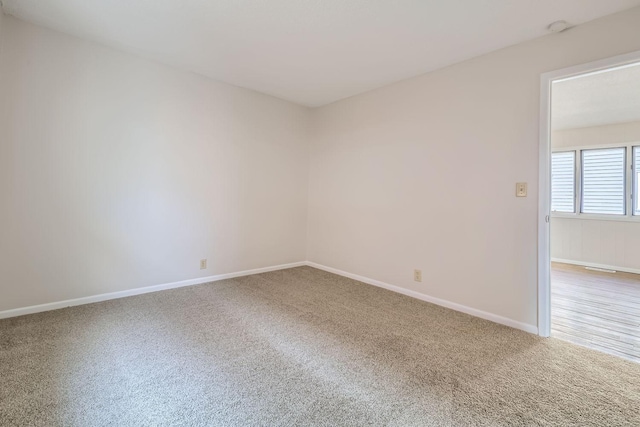 carpeted spare room featuring baseboards