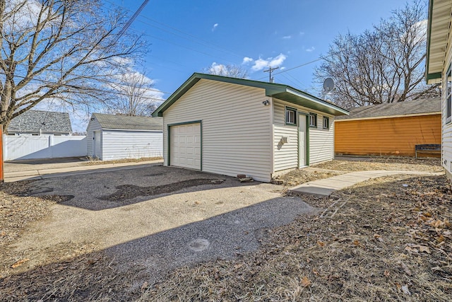 detached garage featuring fence and driveway