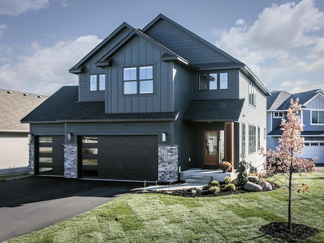 view of front of house with driveway, a shingled roof, an attached garage, board and batten siding, and a front yard