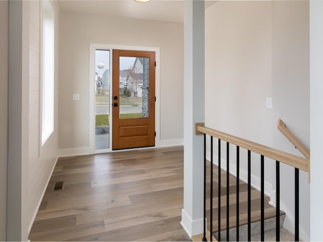 foyer entrance featuring visible vents, baseboards, and wood finished floors