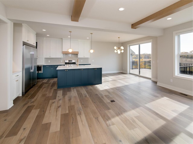 kitchen featuring beam ceiling, light countertops, decorative backsplash, appliances with stainless steel finishes, and white cabinets