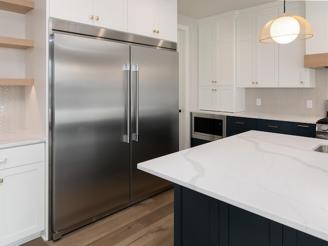 kitchen featuring built in appliances, open shelves, tasteful backsplash, and white cabinetry