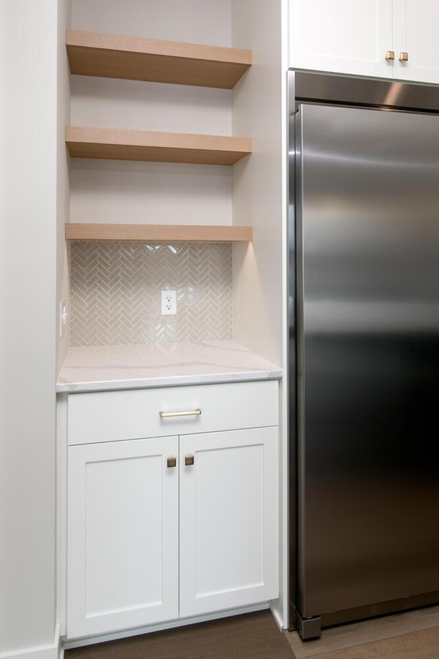 kitchen featuring light countertops, backsplash, open shelves, and stainless steel built in fridge