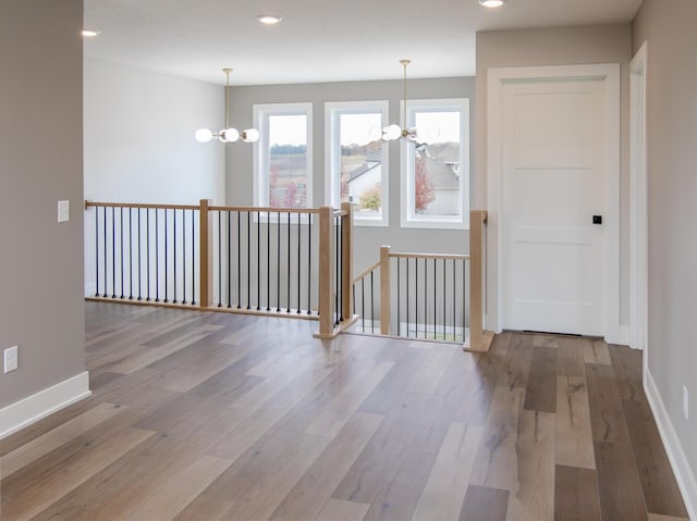 spare room with a chandelier, baseboards, and wood finished floors