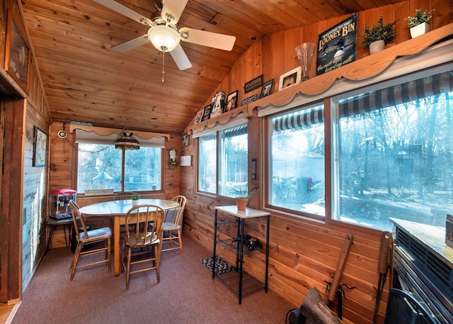 carpeted dining room with vaulted ceiling, wood walls, wood ceiling, and a ceiling fan