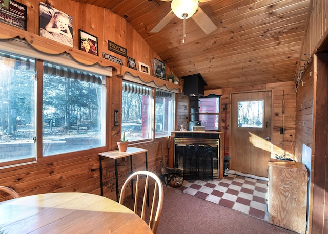 dining space with wooden walls, a ceiling fan, wood ceiling, tile patterned floors, and vaulted ceiling