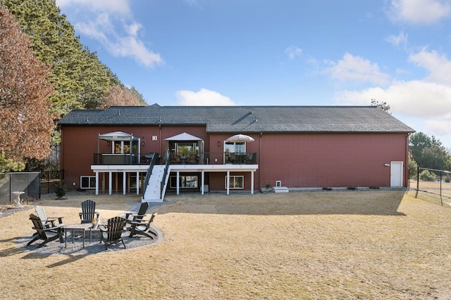 rear view of property with a fire pit, stairs, a deck, and fence