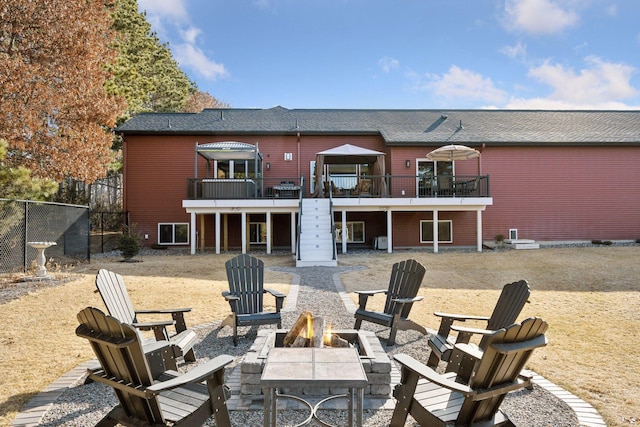 rear view of property featuring a deck, a patio area, a fire pit, and fence