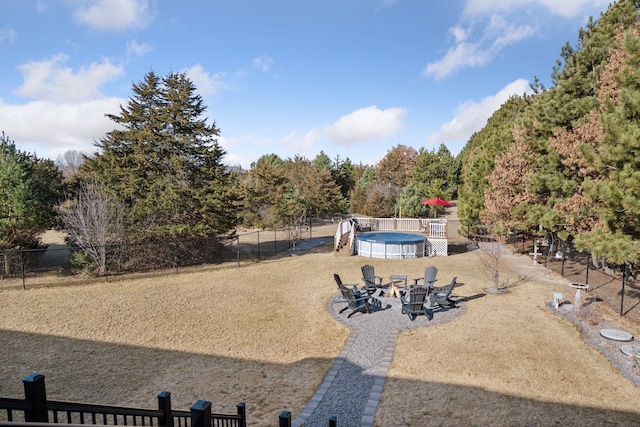 view of yard with a fenced in pool, a fire pit, a patio, and fence