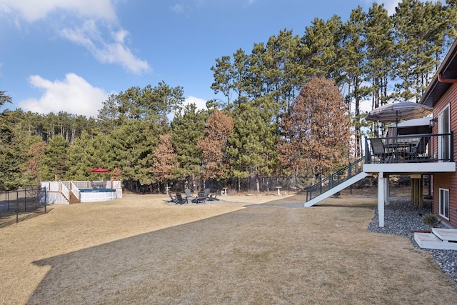 view of yard with a deck, stairway, fence, and a fenced in pool