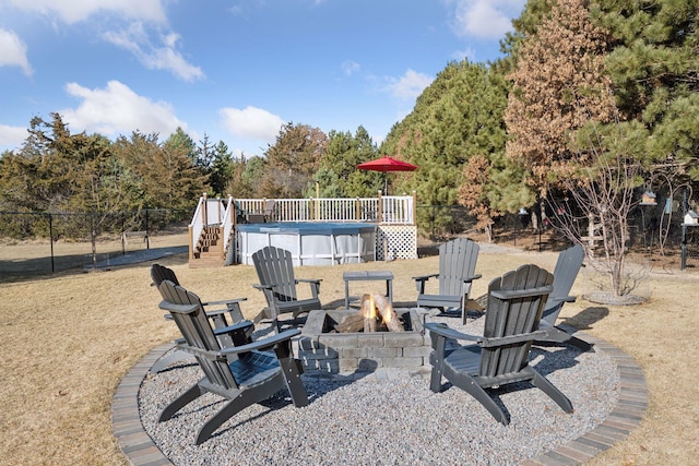 view of yard featuring a wooden deck, a fenced in pool, an outdoor fire pit, and fence