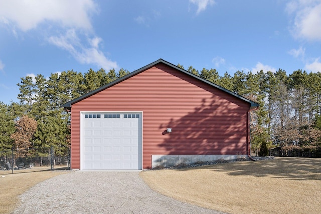 detached garage with gravel driveway and fence