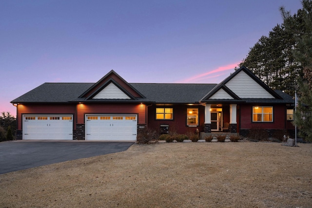 craftsman inspired home with an attached garage, driveway, and roof with shingles