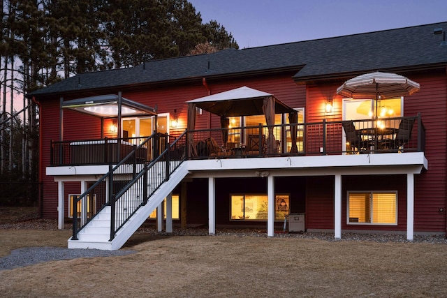 rear view of property featuring a wooden deck, stairway, and a shingled roof