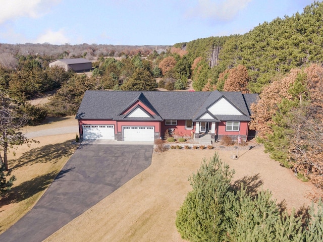 view of front of home featuring a garage, a wooded view, and driveway