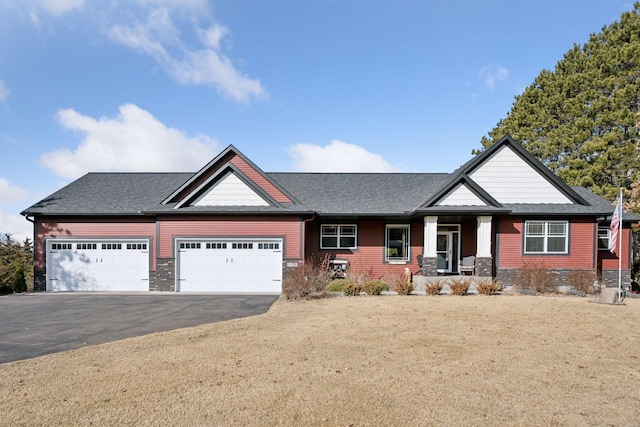 craftsman inspired home with an attached garage, driveway, a front yard, and roof with shingles