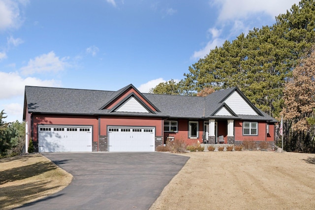 view of front of house with an attached garage, covered porch, driveway, and roof with shingles