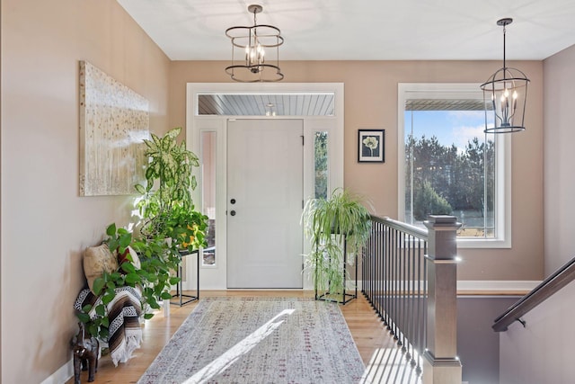 entrance foyer featuring baseboards, an inviting chandelier, and wood finished floors