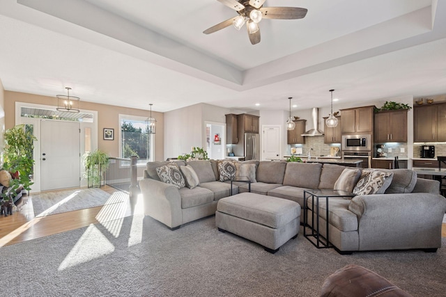 living room with recessed lighting, ceiling fan, a tray ceiling, and wood finished floors