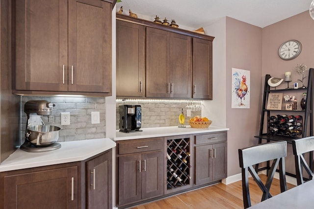 kitchen featuring decorative backsplash, baseboards, light wood-style flooring, and light countertops