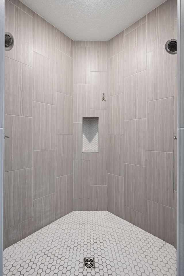 full bathroom featuring a tile shower and a textured ceiling