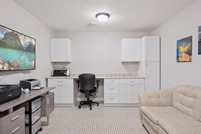 office with a textured ceiling, light floors, and built in study area