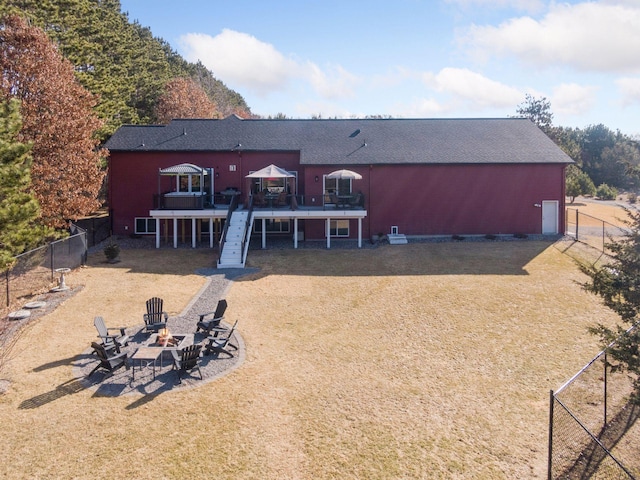 back of house featuring a wooden deck, an outdoor fire pit, a yard, a fenced backyard, and stairs