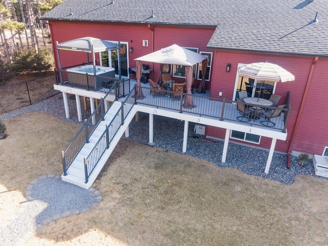 back of property featuring outdoor dining area, roof with shingles, a wooden deck, and a hot tub